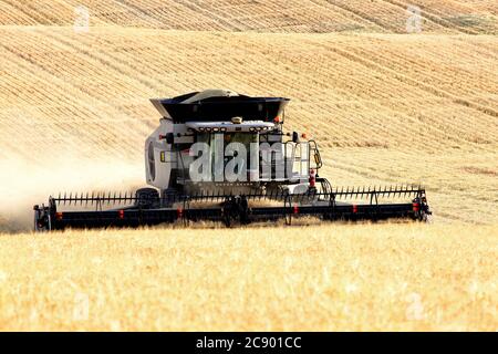 Combines work harvesting wheat in the fertile farm fields of Idaho. Stock Photo