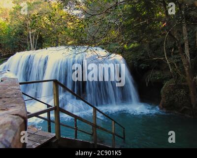 waterfall framed by trees and a wooden staircase. Stock Photo