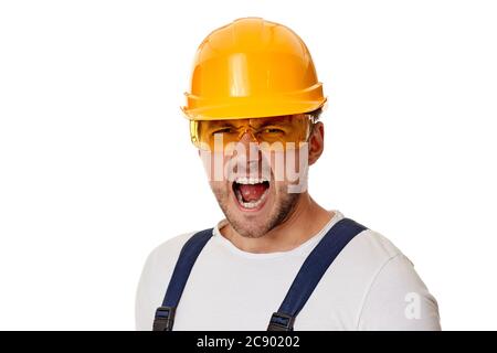 portrait of angry screaming man construction worker in yellow hard hat isolated on white studio background Stock Photo