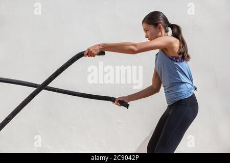 Fitness woman training battle ropes workout at gym. Girl working out arms and cardio using battling rope for cross fit exercises Stock Photo