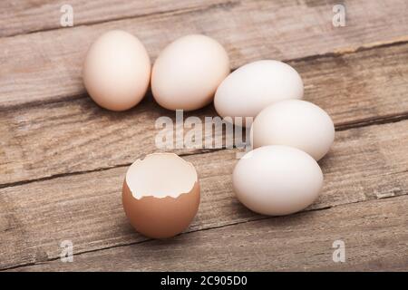 The eggs, the top view which are laid out by a half moon on a wooden table from old boards with the broken egg in the foreground, nobody. Stock Photo