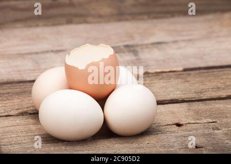The eggs put on a small group on a wooden table from old boards and the cracked egg from above, nobody. Stock Photo