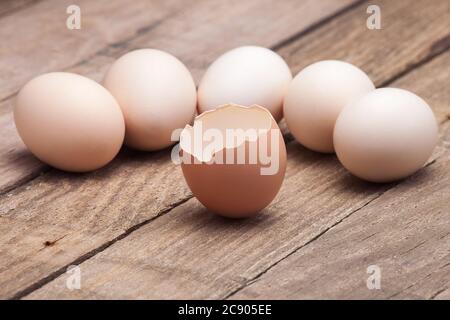 The eggs which are laid out on a wooden table from old boards with the broken egg in the foreground, nobody. Stock Photo