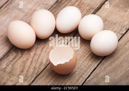 The eggs, the top view which are laid out on a wooden table from old boards with the broken egg in the foreground, nobody. Stock Photo