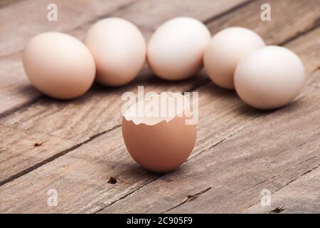 The eggs which are laid out on a wooden table from old boards with the split egg in the foreground, nobody. Stock Photo