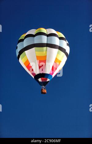 An aerial view of a colorful hot air balloon against a blue sky, floating over the Idaho country side. Stock Photo