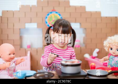 young girl pretend play babysitting with baby doll at home Stock Photo
