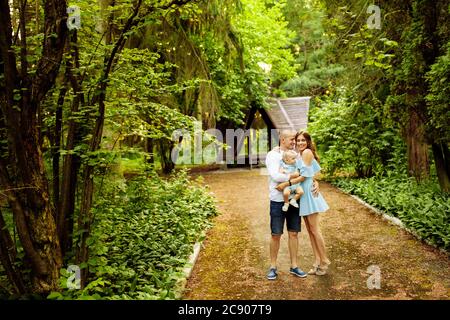Overjoyed young family walking at the park, hugging, smiling Stock Photo
