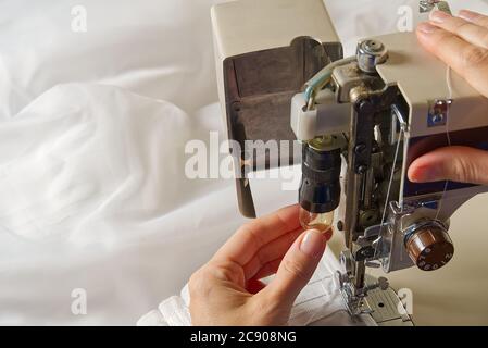 Woman's hands setting sewing machine. worker changing bulb in sewing machine. Stock Photo