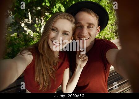 A couple makes a joint photo. The boy and girl makes selfie on phone. A young couple takes selfie. Stock Photo