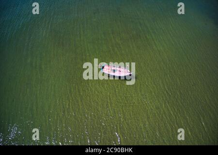 This unique photo shows the beach of Pak Nam Pran in Thailand photographed from above with a fishing boat that is anchored on the beach. Stock Photo