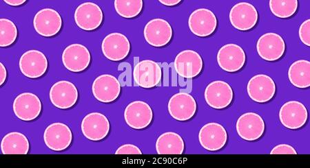 Seamless pattern pink citrus fruit orange lemon lying on violet surface. Colorful fresh citrus slice wallpaper. Creative vivid vibrant color, summer Stock Photo