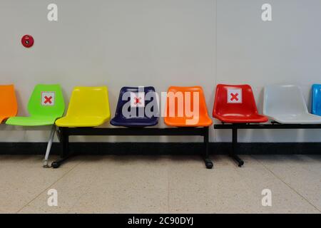 Some chairs in waiting area are forbidden by marking with cross symbol, physical distancing due to coronavirus pandemic, selective focus Stock Photo