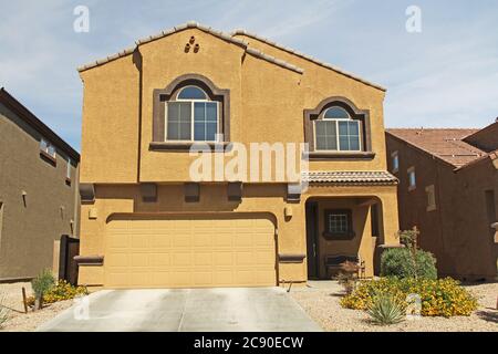 New two-story, brown and mustard yellow stucco home in Tucson, Arizona, USA with beautiful blue sky and landscaping. Stock Photo