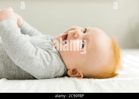 Smiling baby boy lying on bed Stock Photo