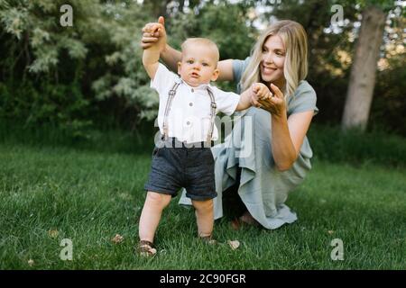 Mother with baby son learning to walk in park Stock Photo
