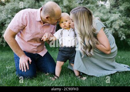 Parents kissing baby son in garden