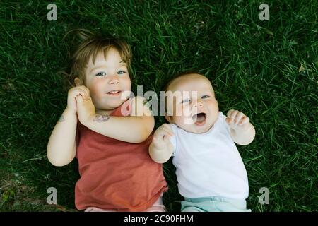 Portrait of happy siblings lying in grass Stock Photo