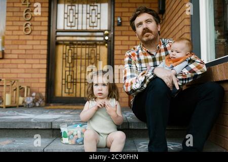 Father with kids sitting on porch Stock Photo