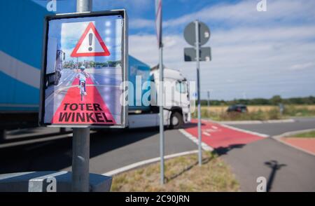 Garbsen, Germany. 23rd July, 2020. A truck turns right at an intersection, while a sign saying 'blind spot' of a protection system lights up brightly and warns cyclists. Although truck drivers look in the mirror when turning, the cyclists in the blind spot are overlooked. Again and again, fatal accidents follow. The protection system called Bike Flash is designed to protect cyclists from turning trucks. Credit: Julian Stratenschulte/dpa/Alamy Live News Stock Photo
