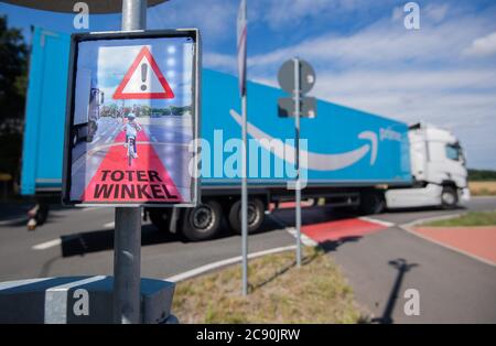 Garbsen, Germany. 23rd July, 2020. A truck turns right at an intersection, while a sign saying 'blind spot' of a protection system lights up brightly and warns cyclists. Although truck drivers look in the mirror when turning, the cyclists in the blind spot are overlooked. Again and again, fatal accidents follow. The protection system called Bike Flash is designed to protect cyclists from turning trucks. Credit: Julian Stratenschulte/dpa/Alamy Live News Stock Photo