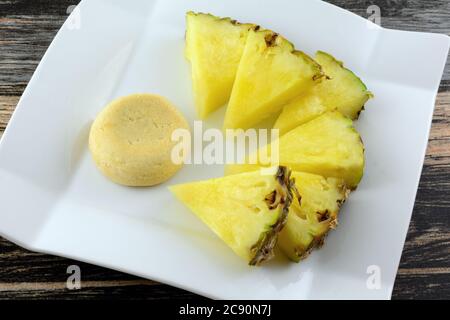 Pineapple shortbread cookie with pineapple filling and fresh pineapple wedges on white dessert plate Stock Photo