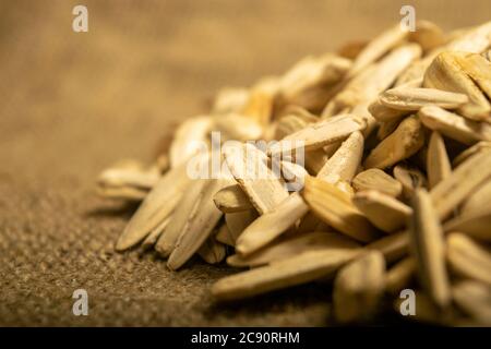 White sunflower seeds fried with sea salt in bulk on a background of coarse-textured burlap. Close up Stock Photo