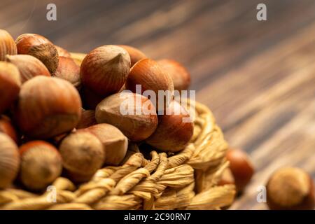 Hazelnuts in a wicker basket and hazelnuts scattered on a wooden background. Close up Stock Photo