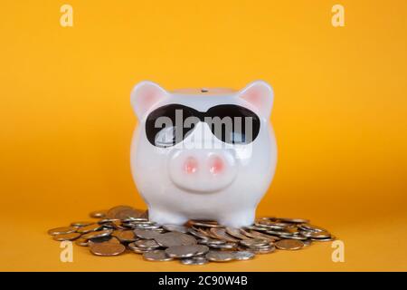 Piggy bank with coin pile on yellow background, space for text. Finance, saving money. Business to success and saving for retirement concept Stock Photo