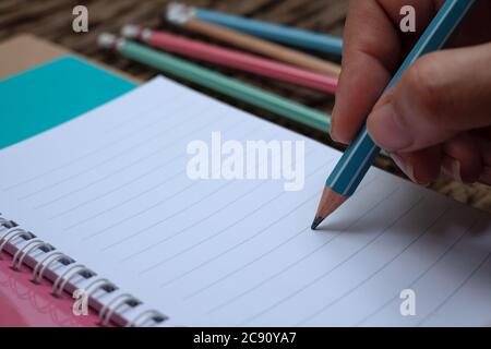 Hand holding pencil and book at wood desk background Stock Photo