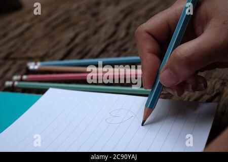Hand holding pencil and book at wood desk background Stock Photo