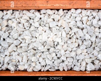 White pebble background. Stone gravel texture in terracotta pot, top view. Stock Photo