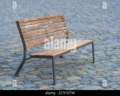 wooden iron classic empty bench on street city gray cobblestone pavement Stock Photo