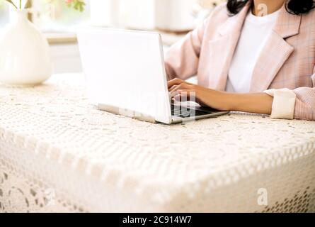 Woman sitting at the table and working at laptop. Stock Photo
