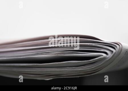 Folded newspapers on black table and white background, with narrow depth of field Stock Photo