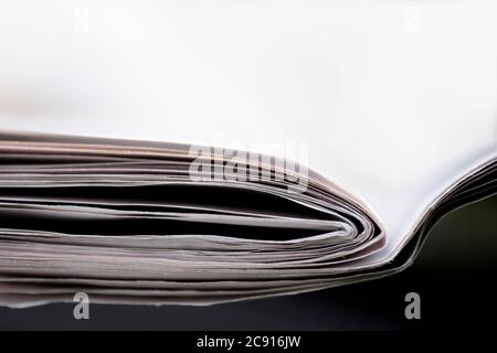 Folded newspapers on black table and white background, with narrow depth of field Stock Photo