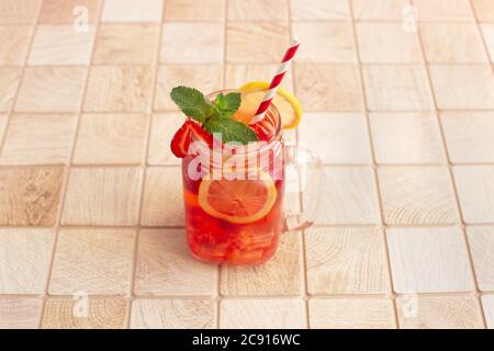 Fresh strawberry cocktail. Cold Strawberry lemonade with lemon and ice in mason jar on a wooden table Stock Photo