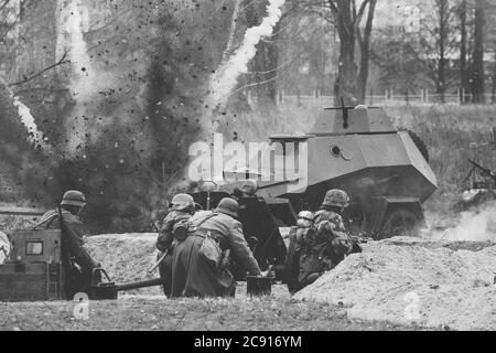 Re-enactors Dressed As German Soldiers In World War II Are Fighting Shooting With A Cannon On The Russian Soviet Armored Car During Historical Stock Photo
