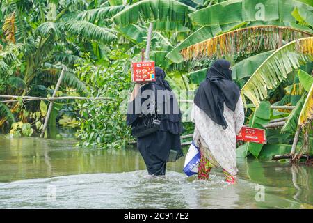 Dhaka, Dhaka, Bangladesh. 27th July, 2020. Woman's are walks through floodwater street at Sreenagar in Munshiganj near Dhaka, Bangladesh on July 27, 2020. Credit: Zabed Hasnain Chowdhury/ZUMA Wire/Alamy Live News Stock Photo