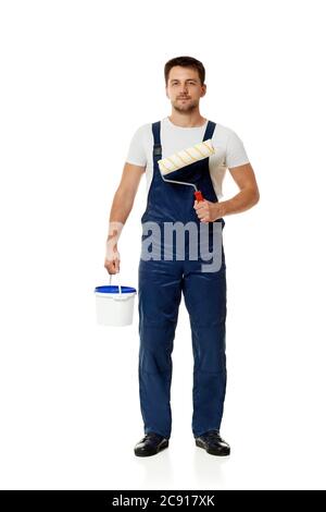 caucasian repairman in blue uniform holding paint roller and can with paint. builder or painter decorator isolated on white background Stock Photo