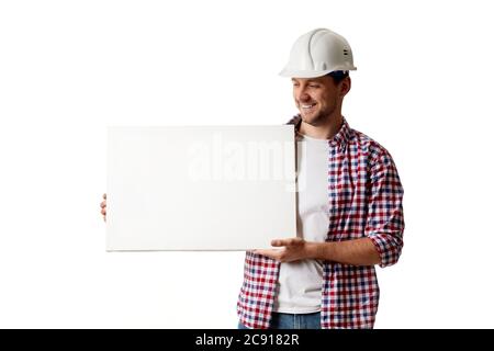 smiling handyman worker in hard hat holding empty blank board. builder in shirt isolated on white studio background Stock Photo