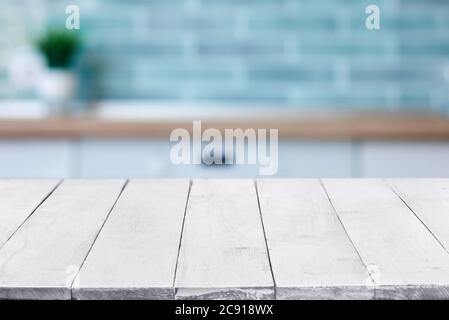 Empty perspective, white wooden boards or table top against blurred kitchen interior on background. May be used as template and mockup for display or Stock Photo