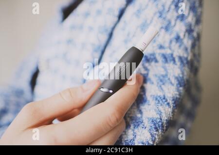 Heating tobacco system IQOS 3 in woman hand. Stock Photo