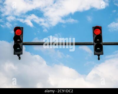 Two traffic lights showing red color against blue sky. Stock Photo