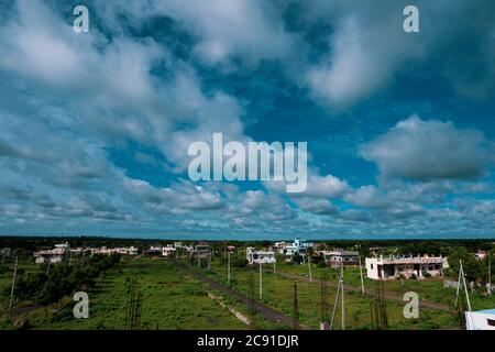 a long view of city landscape with blue sky, clouds & green land Stock Photo