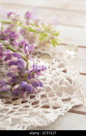 Purple lupin flowers with vintage lace on white background. Lupinus, lupine. Tender card, vertical image Stock Photo