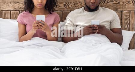 Cropped of man and woman using mobile phones in bed Stock Photo