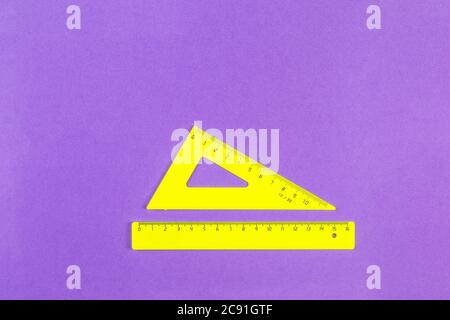School drawing tools. Yellow triangle and ruler on a purple background. School stationery. Flat Lay, Copy space, top view, space for text Stock Photo