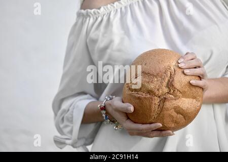 Woman holding a round loaf of freshly baked crusty bread in her hands in a close up cropped view Stock Photo
