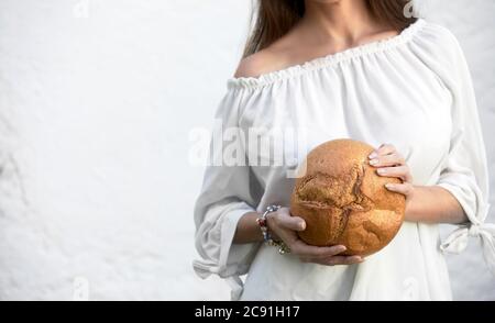 Freshly baked crusty round loaf of bread being held in the hands of a young woman with the crust displayed to the camera and copy space Stock Photo
